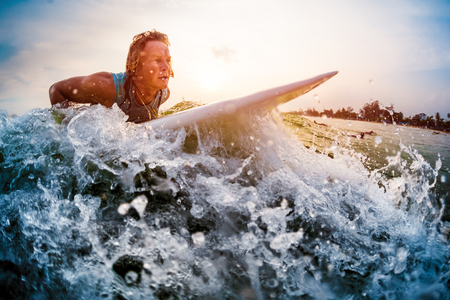 Young man surfer trying to catch the wave