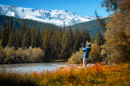Amateur angler fishing on the rapid river with mountains on the background. Altai, Russiaの写真素材