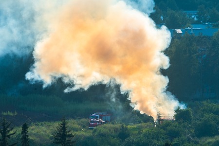 Fire in the forest with smoke close to a city and fire trucksの写真素材