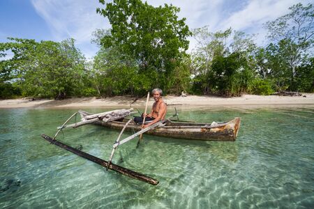SULAWESI, INDONESIA - APRIL 29, 2011: Happy local fisherman paddles his wooden boat in the calm sea of the Gulf of Tominiのeditorial素材