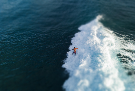 Aerial view of the surfer riding the ocean wave. Oahu, Hawaii. Tilt shift effect appliedの写真素材