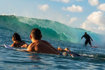 OAHU / USA - 06 DECEMBER 2018: Local Hawaiian surfers paddle to the line up and watch how other guy rides the wave. Tracks surf spot on the West coast of Oahu.のeditorial素材
