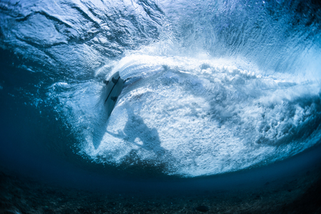 Underwater view of the surfer riding clear ocean wave and making sharp turnの写真素材