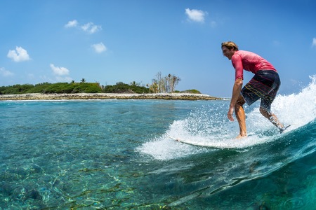 Happy surfer rides the funny, crystal clear, tropical waveの写真素材