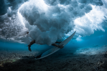 Underwater shot of the male surfer trying to get out from the broken waveの写真素材