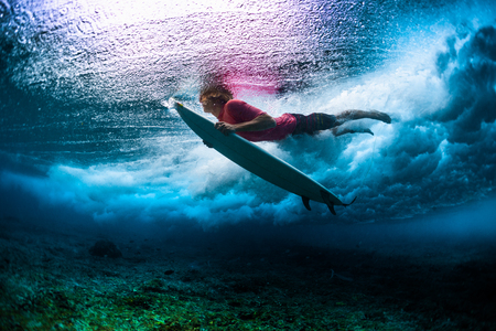 Young male surfer dives under the breaking ocean waveの写真素材