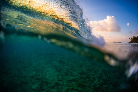 Ocean wave breaking over the reef at sunsetの写真素材