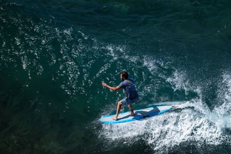 MAUI / USA - 14 DECEMBER 2018: Young longboard surfer tries to do nose riding trick while glides on the wave at Honolua surf spot on the north of Maui, Hawaiiのeditorial素材