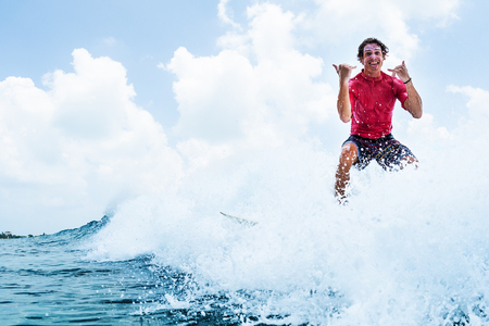 Happy surfer rides the wave and shows the Shaka signの写真素材