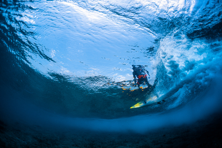 Underwater view of the surfer riding the crystal clear ocean waveの写真素材