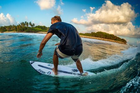 MALDIVES / HURAA - 22 MARCH 2019: Professional surfer rides ocean wave at Honkeys surf spot during...