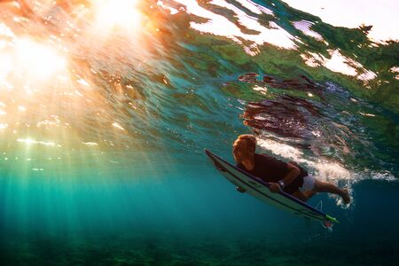 MALDIVES / HURAA - 23 MARCH 2019: Underwater view of the young male surfer diving with his surfboardのeditorial素材