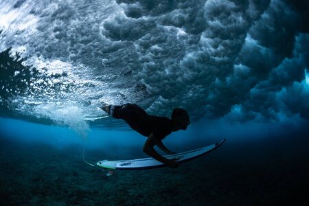 MALDIVES / HURAA - 23 MARCH 2019: Male surfer dives under the huge broken wave with his surfboardのeditorial素材