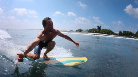 Young man rides the tropical ocean wave on fun board and shows the Shaka signの写真素材