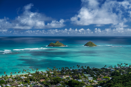 Hawaiian tropical coast with buildings among the palm trees and two islands in the Pacific Oceanの写真素材