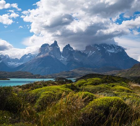 Torres del Paine National Park with snow capped mountains (Cordillera Paine) covered in the clouds and lush green vegetation on the foreground. Chileの写真素材