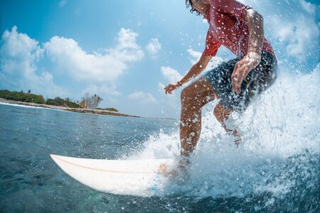 Young caucasian man surfs the ocean wave and makes a lot of splashes into the camera. Chickens surf spot in Maldivesの写真素材