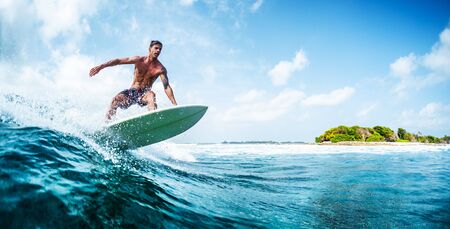 HIMMAFUSHI / MALDIVES - MARCH 10, 2019: Panorama of the young surfer with lean muscular body riding the tropical waveのeditorial素材