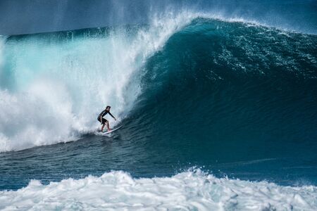 OAHU / USA - DECEMBER 05, 2019: Surfer rides giant wave at the famous Banzai Pipeline surf spot...