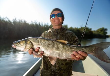 Happy fisherman holds the Asp fish and smilesの写真素材