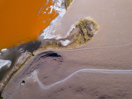 Aerial top down view of the salty lake named Laguna Colorada in Bolivian Altiplano and the road leading to observing area. Road leads to the view point through the desertの写真素材