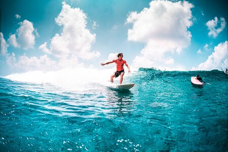 Surfer in red shirt rides the ocean waveの写真素材