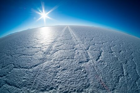 Car tracks on the surface of the Salar de Uyuni salt flat in Boliviaの写真素材
