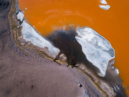 Aerial top down view of the salty lake named Laguna Colorada in Bolivian Altiplano, lake has orange color and white areas are the saltの写真素材