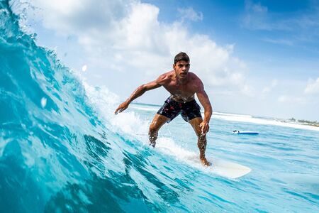 Young athletic surfer rides the ocean wave on Sultans surf spot in Maldivesの写真素材