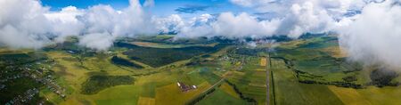 Aerial panorama of the rural area with green fields and fluffy clouds in the skyの写真素材
