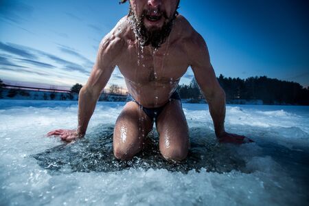 Young man with beard swims in the winter lakeの写真素材