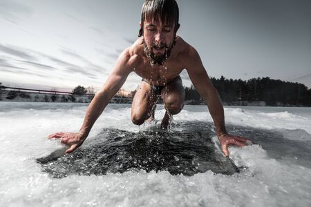 Young man with beard swims in the winter lakeの写真素材