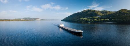 Cargo ship moves on the river of Volga near the city of Samara with Zhiguli Mountains on the background. Russiaの写真素材