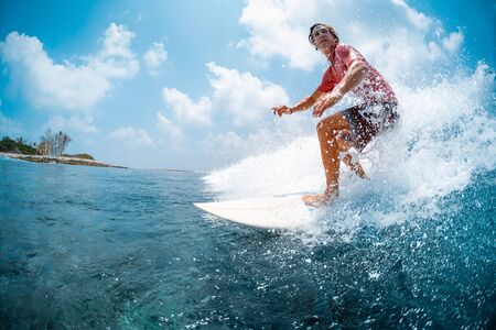 Young caucasian man surfs the ocean wave and makes a lot of splashes into the camera. Chickens surf spot in Maldivesの写真素材