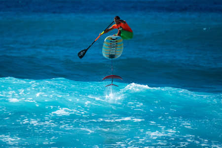 OAHU, HI / USA - DECEMBER 01, 2018: Surfer jumps on a hydrofoil surfboard and shows the finsのeditorial素材