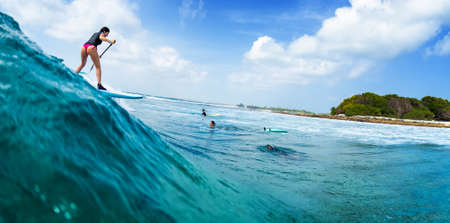 HURAA , MALDIVES MARCH 10, 2019: Young woman surfs the wave on the Sultans surf spot in Maldivesのeditorial素材