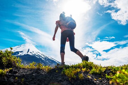 Young woman hiker walks on the trail with snow capped volcano of Osorno on the background, Chilean Patagoniaの写真素材