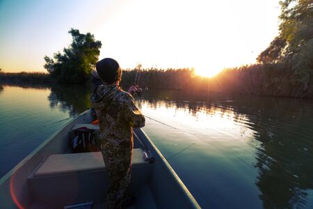 Anglers fishing from the boat on the calm river in Astrakhan Region in Russia. Astrakhan is a famous fishing destinationの写真素材