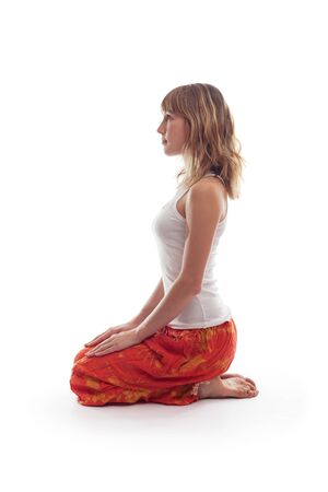 Young woman in white shirt sits in yoga pose and looks forward. Person is isolated on white backgroundの写真素材