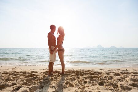 Young happy couple stand on the tropical beach. Man and woman standing together and enjoying pleasant weather on the beachの写真素材