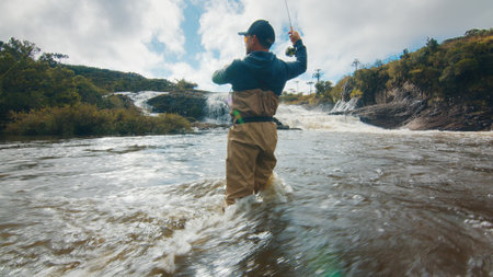 Fly fishing. Fisherman in waders fishing on the rapid riverの写真素材