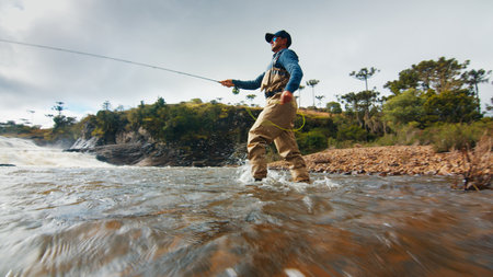 Fly fishing. Fisherman in waders fishing on the rapid riverの写真素材