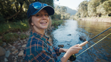 Woman angler on the river. Portrait of the young woman on the river with fishing rodの写真素材