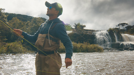 Fly fishing. Fisherman in waders fishing on the rapid riverの写真素材