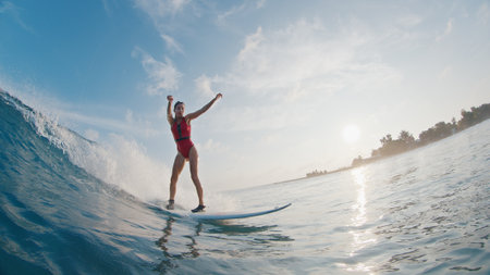 Girl surfer rides the wave. Woman in red suit surfs the ocean wave in the Maldivesの写真素材