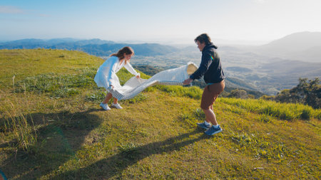 Family have picnic on the green hill in the mountains at sunriseの写真素材