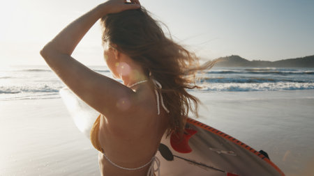 Woman surfer walks with surfing board on the tropical beach