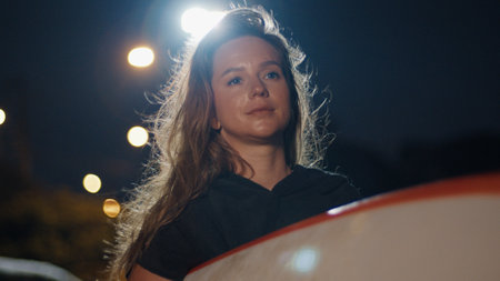 Woman surfer walks at night with surfing boardの写真素材