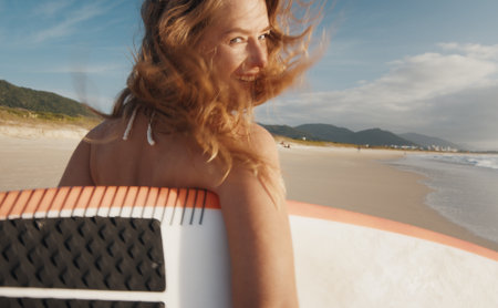 Woman surfer walks with surfing board on the tropical beachの写真素材