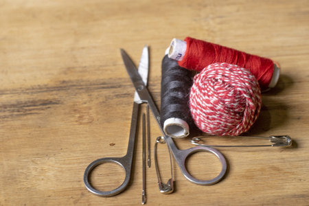 Essential tailoring tools with spools of thread and safety pins arranged on a textured wood background ideal for craft or repair concepts.